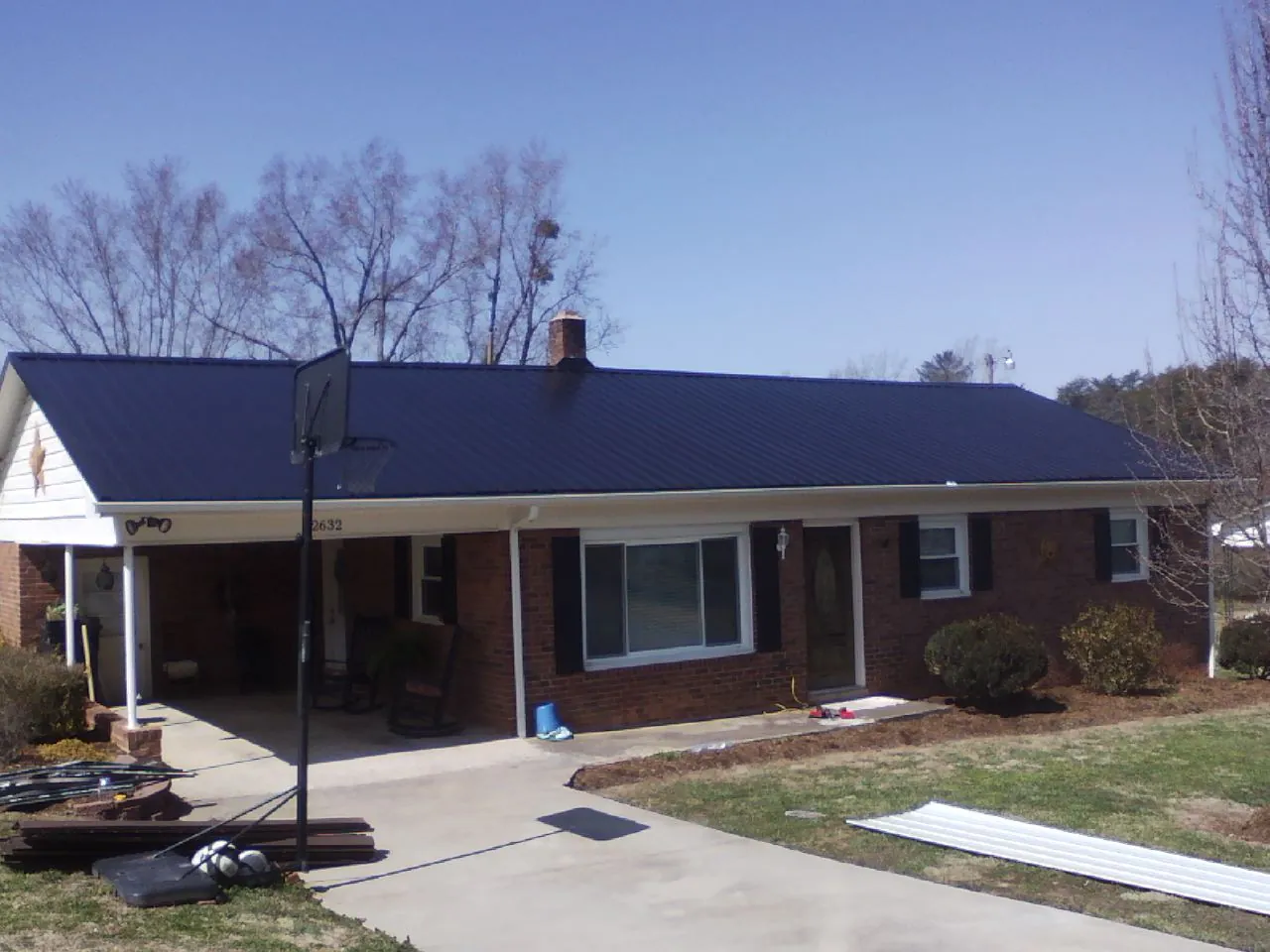Finished dark blue metal roof on a brick ranch with a carport in Hodges