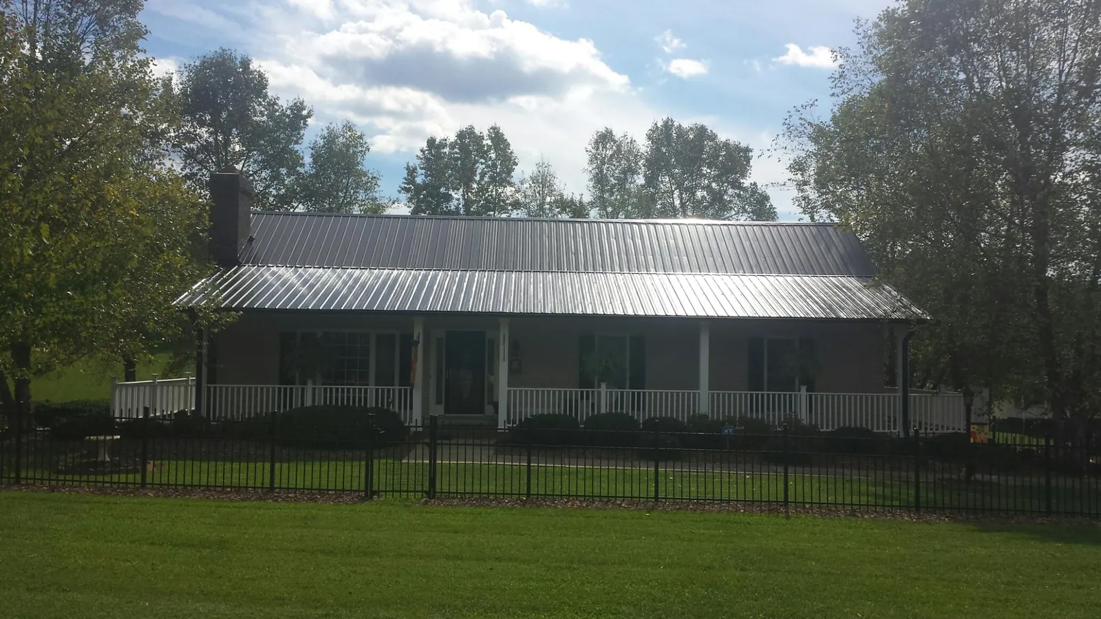 Gray metal roof on a brick ranch with a full width front porch — Gutter Guard Installation work by our crew in Hodges