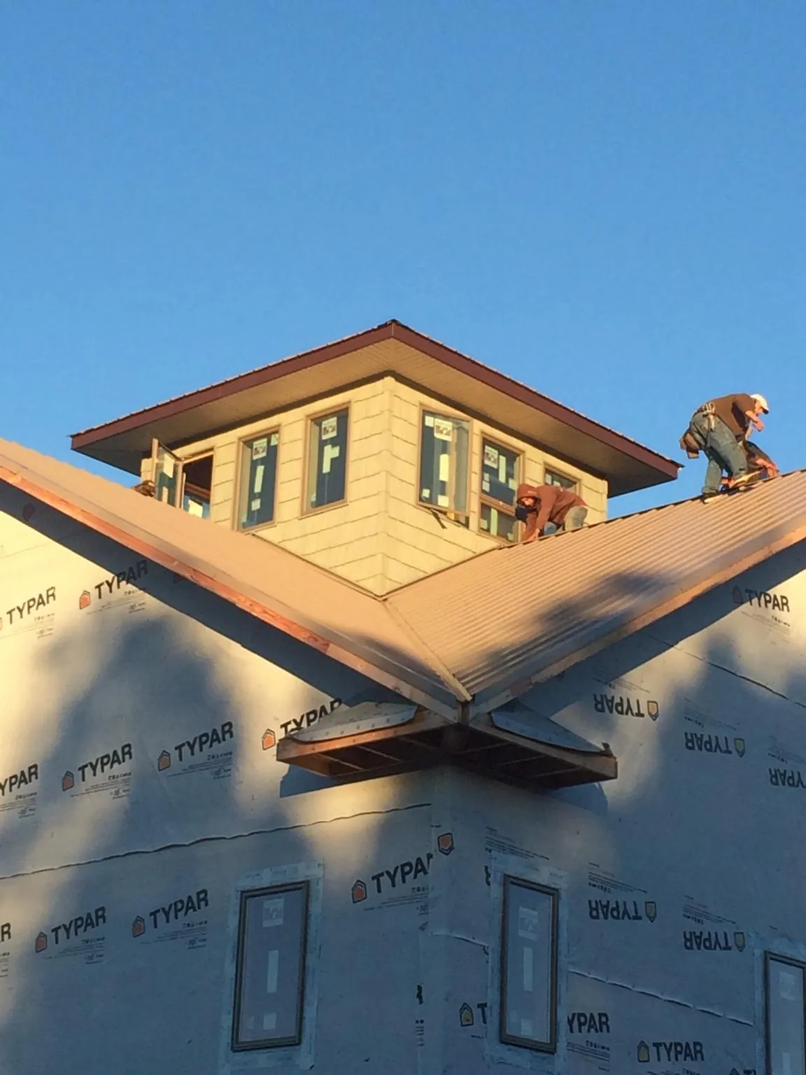 Roofers working around a rooftop cupola on a new metal roof at sunset — Roof Waterproofing in Hodges by Roofing Brothers